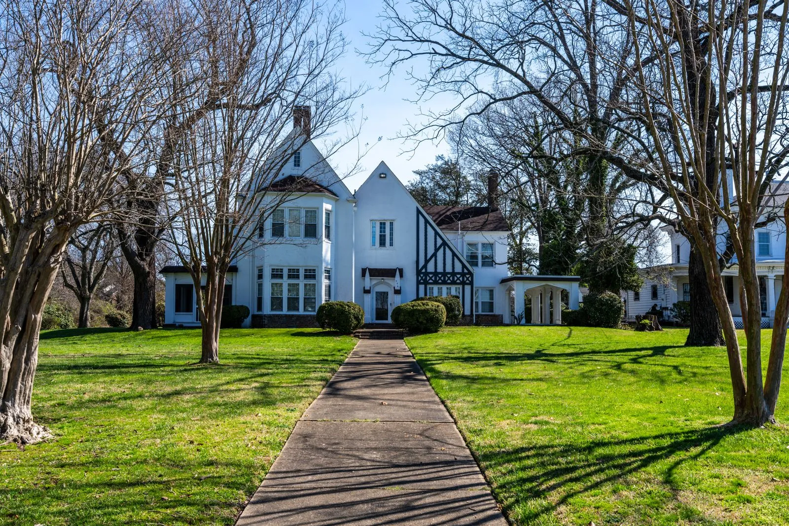 Elegant Tudor Revival style house with symmetrical architecture and lush green lawn in Hampton, Virginia.